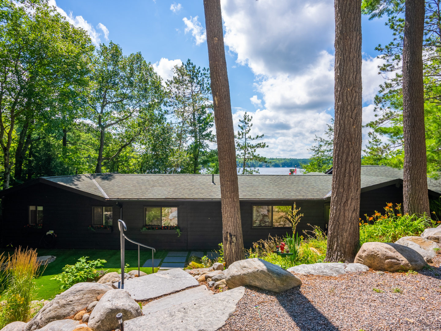 A large cottage with a landscaped exterior and trees all around.