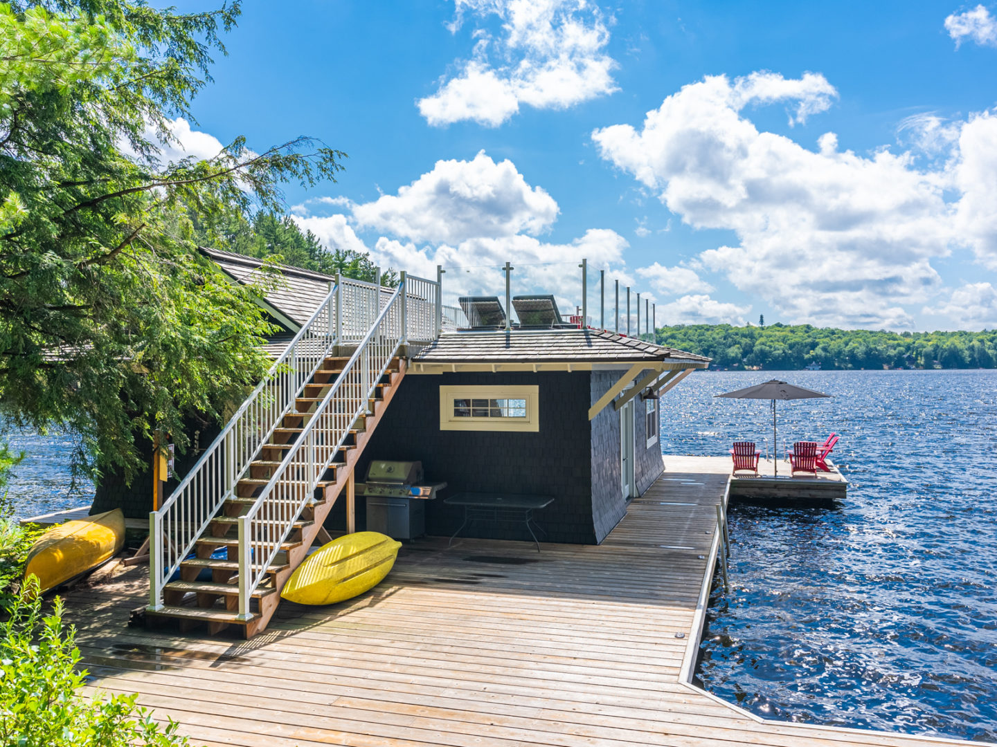 The back of a boutique boathouse, which has a huge dock and stairs leading up to a rooftop deck area.