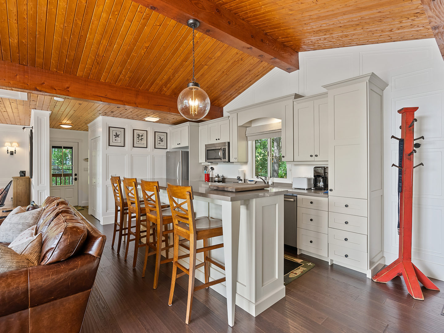 A modest-sized cottage kitchen with an island, barstools and modern appliances.