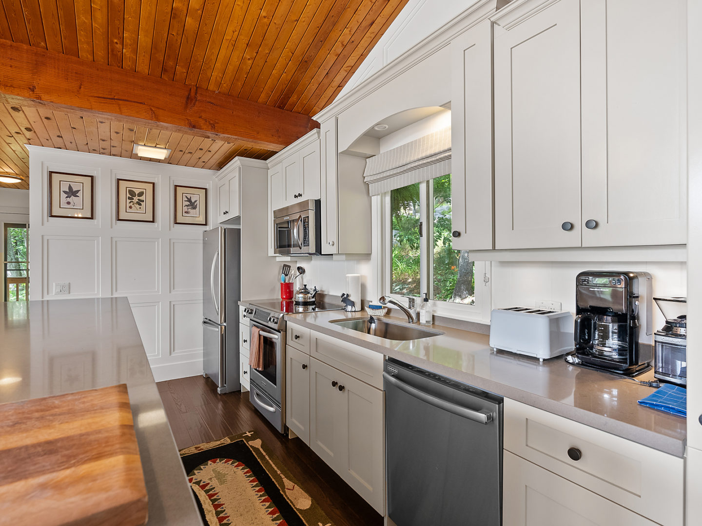 A modest-sized cottage kitchen with white cabinets and modern appliances.