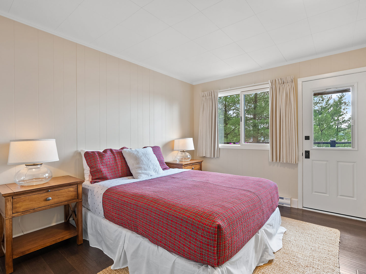 A bright bedroom with a bed and a door leading to an outdoor deck.
