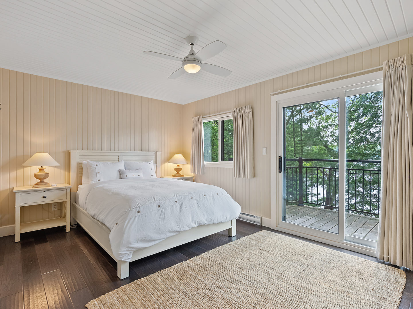 A bright primary bedroom with a double-door exit to an outdoor deck.