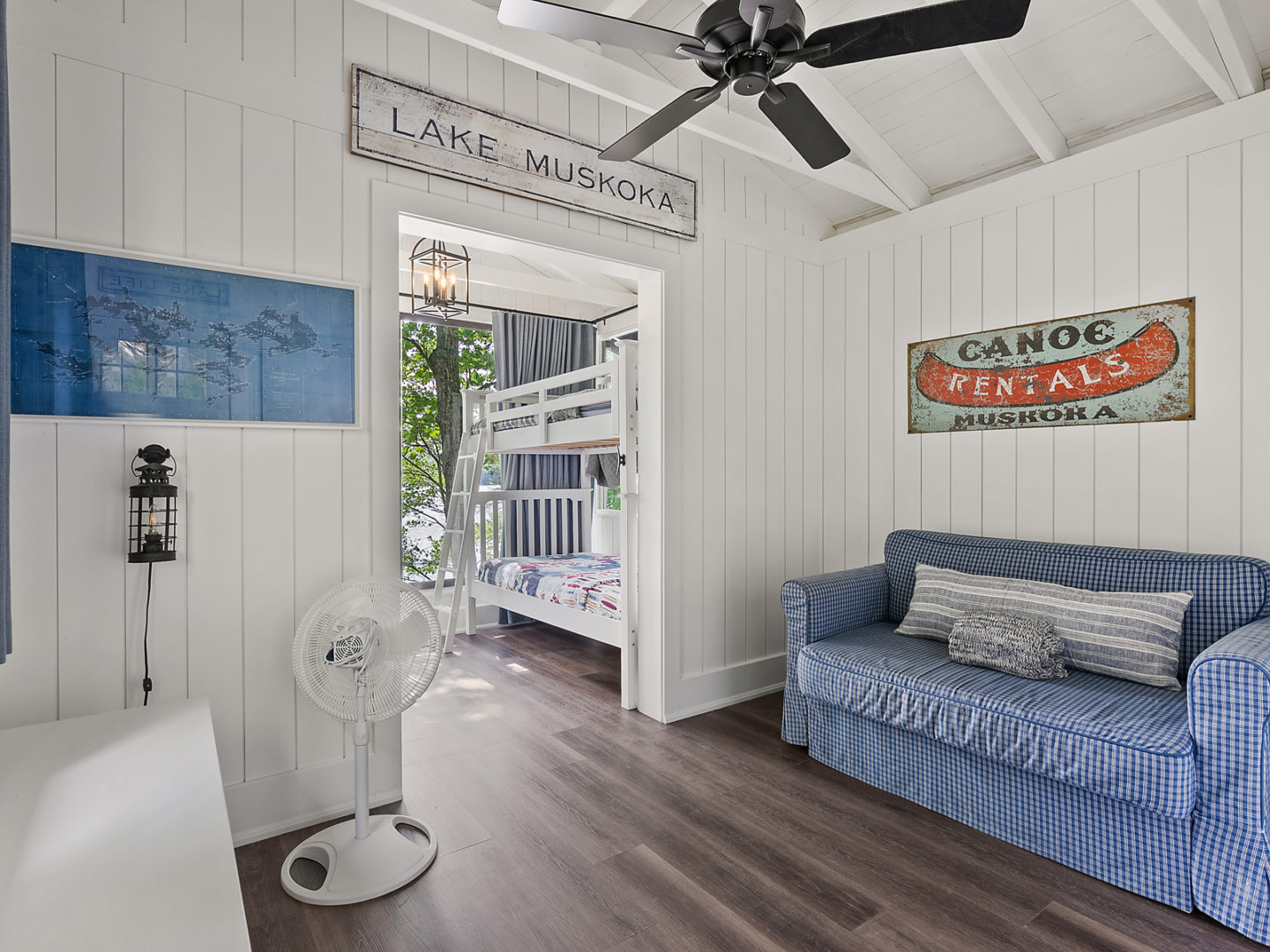 A small living space in a bunkie with a couch, leading into a small bedroom.