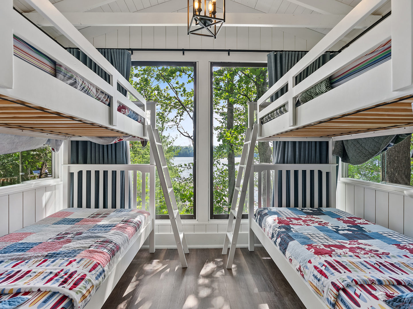 A small bedroom in a bunkie with two sets of bunk beds and a large window.