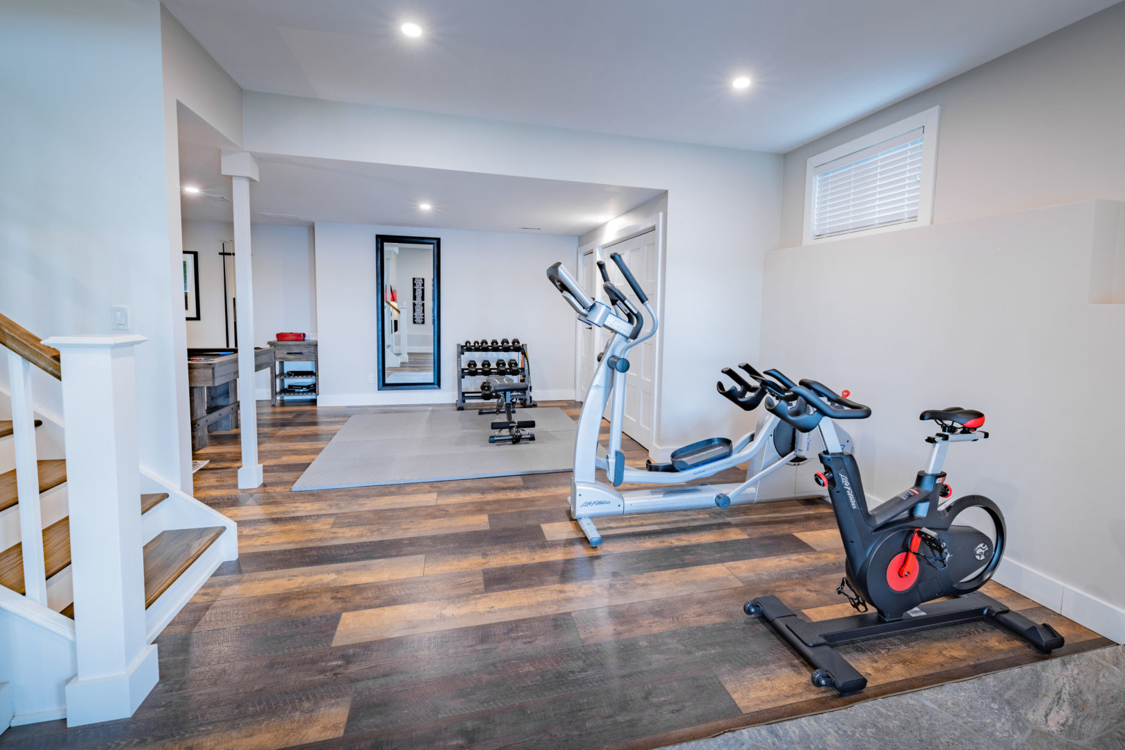 A finished basement area with hardwood floors and gym equipment.