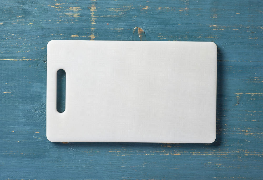 A white plastic cutting board on a blue table