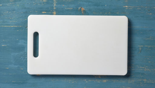 A white plastic cutting board on a blue table
