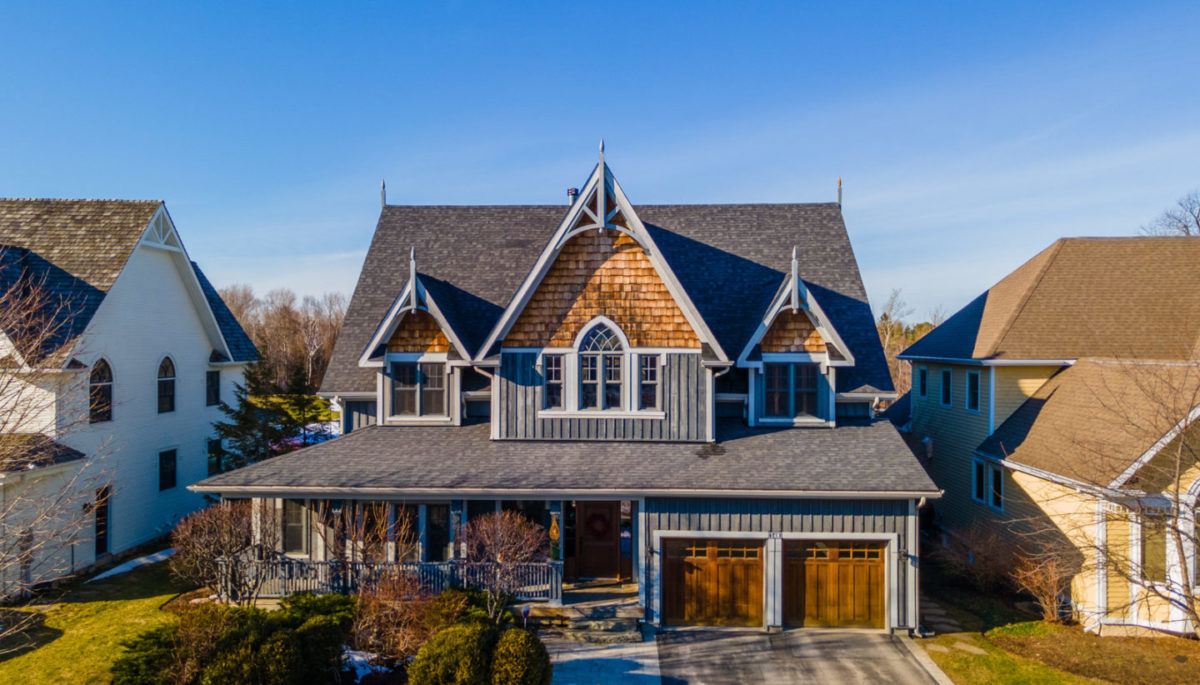 Exterior of the front of a large luxury home with light wooden accents.