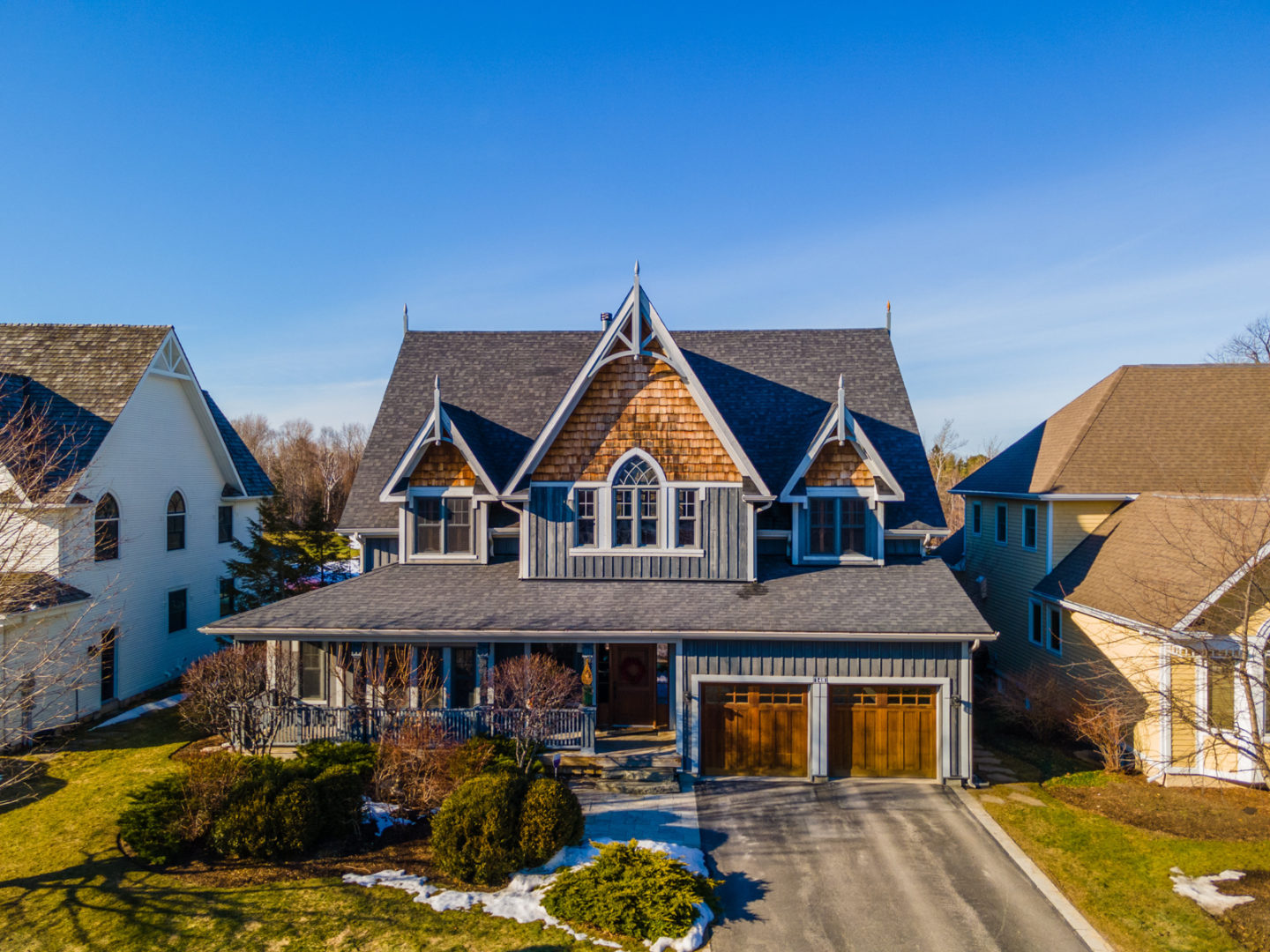 Exterior of the front of a large luxury home with light wooden accents.