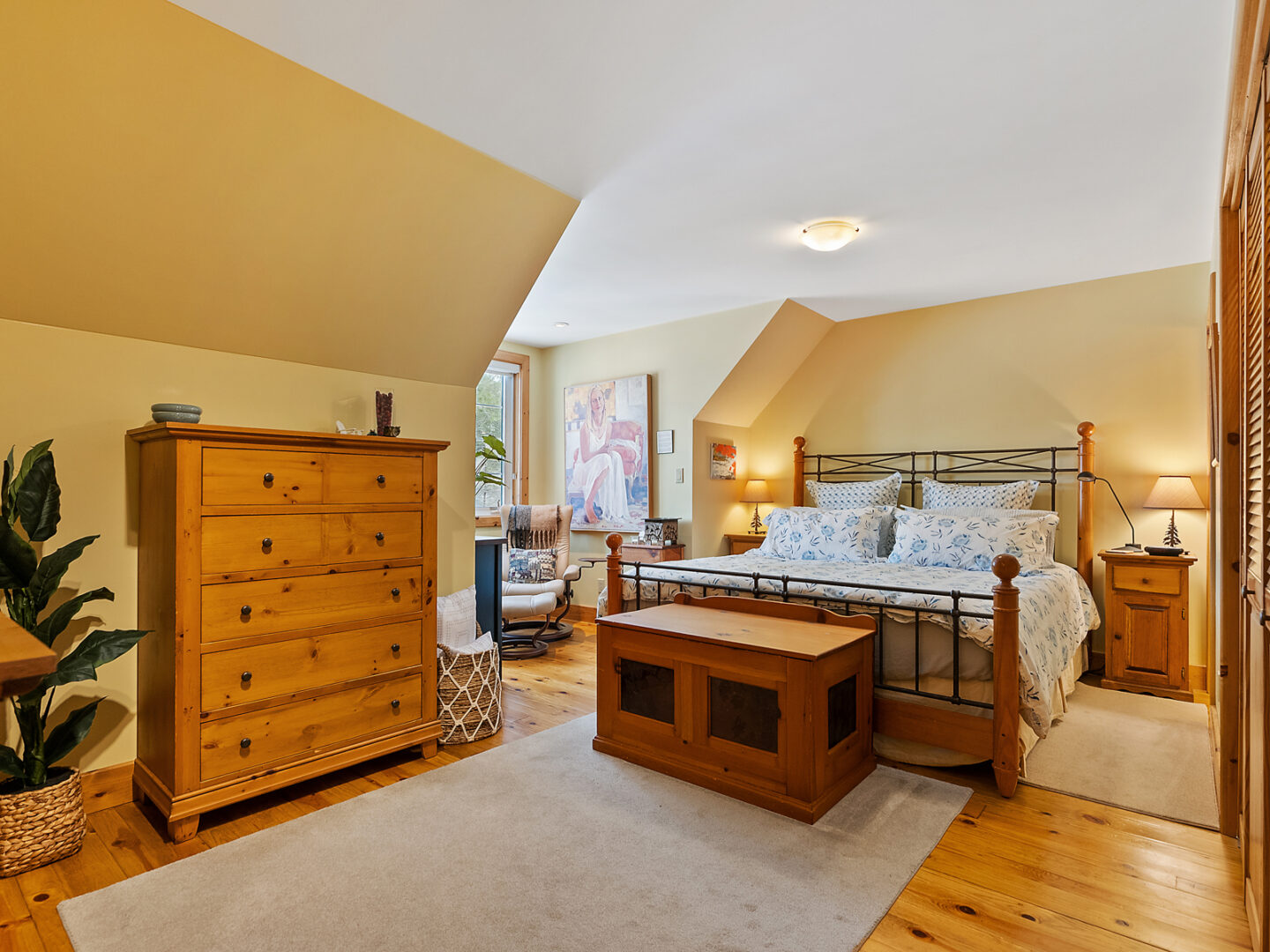 A big, bright bedroom with a large bed, a dresser, and a window.