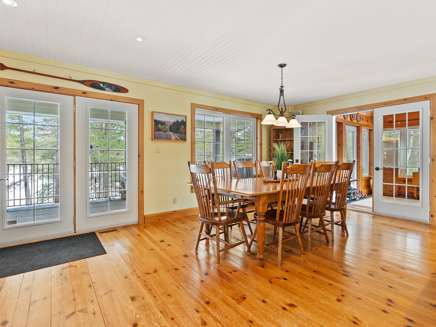 A bright, spacious open-concept dining area with a table and chairs, lots of windows, and warm hardwood floors.