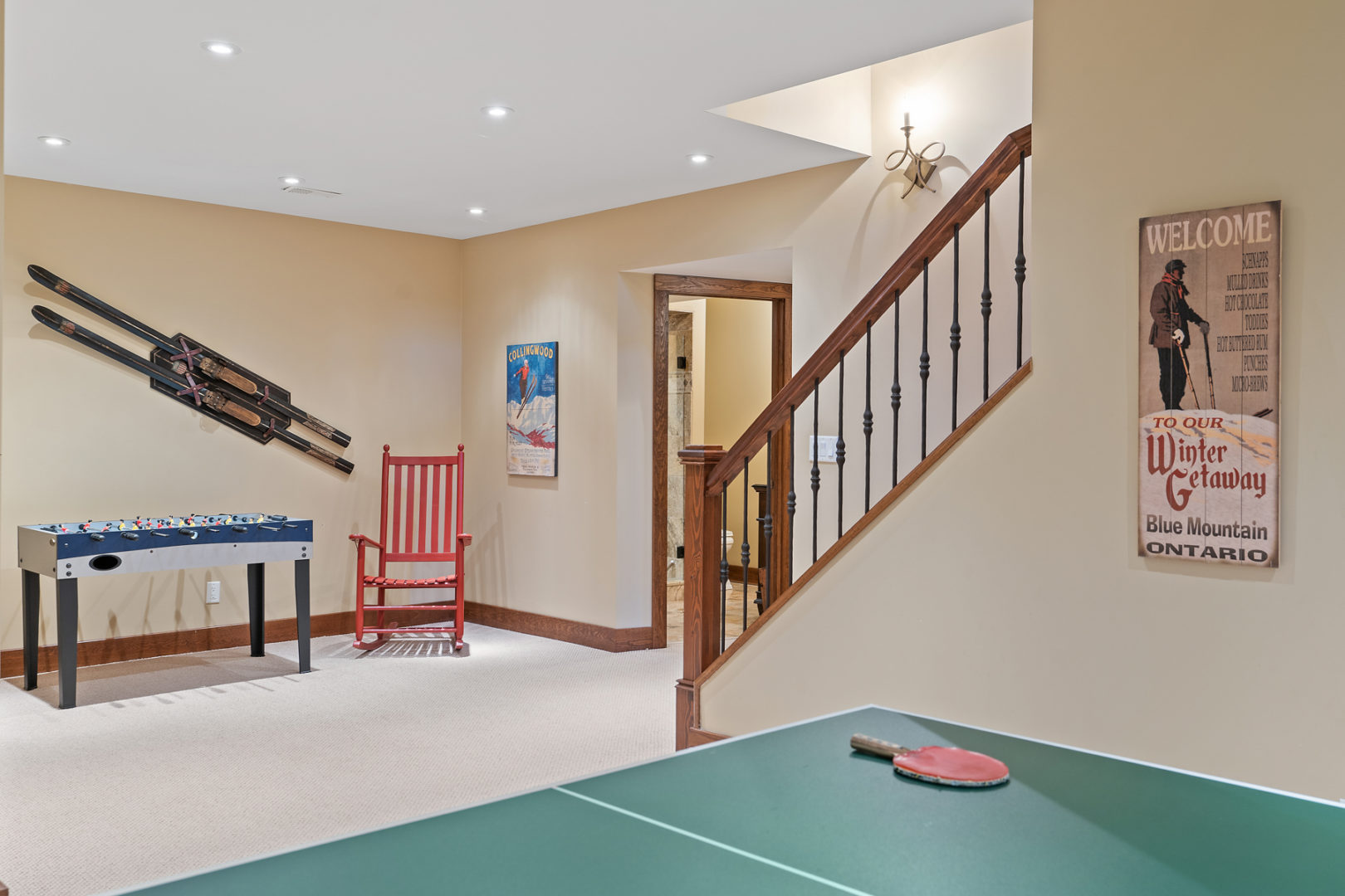 A finished basement of a luxury home, with a ping pong table and an air hockey table.