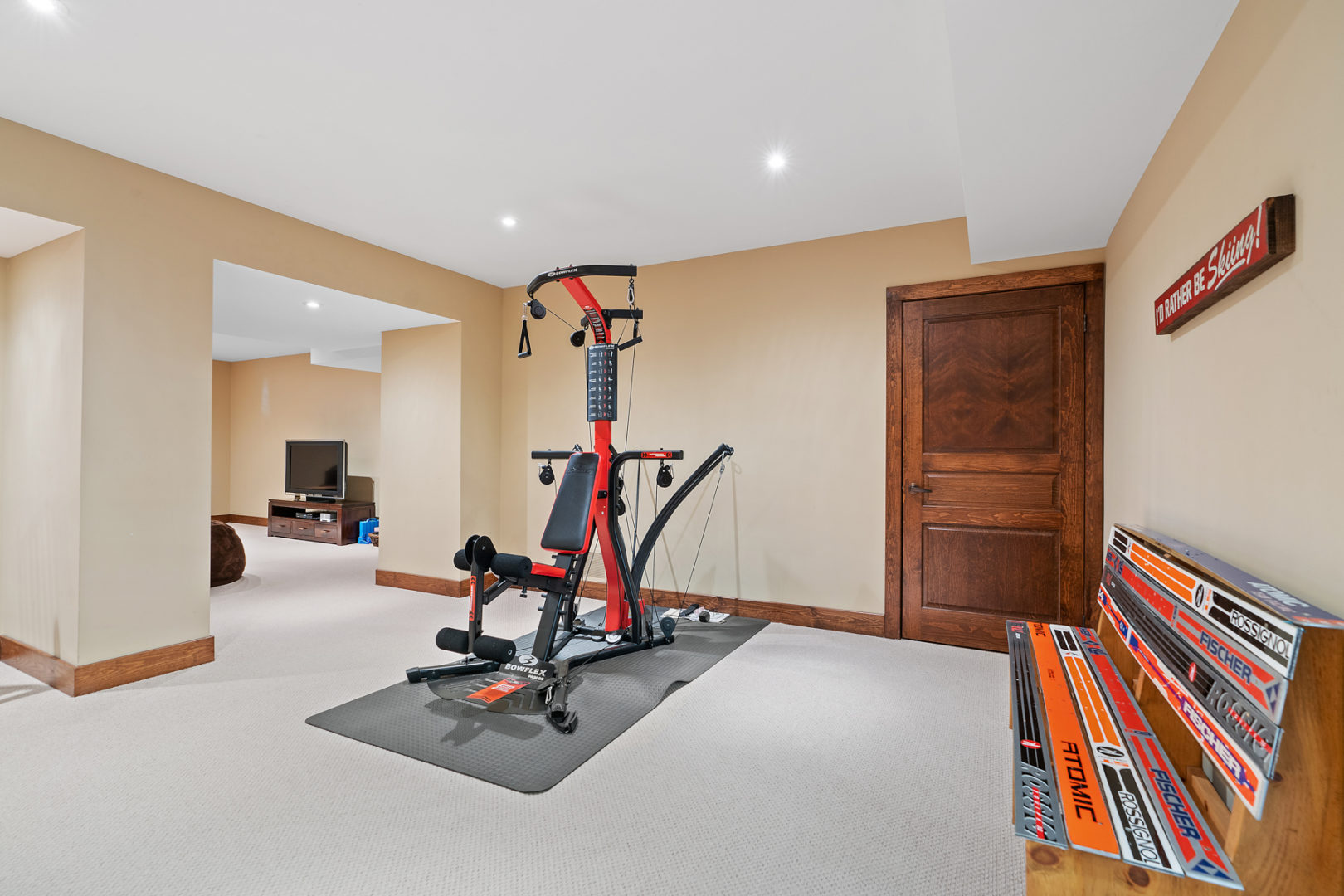 Gym equipment in a spacious and well-lit finished basement.
