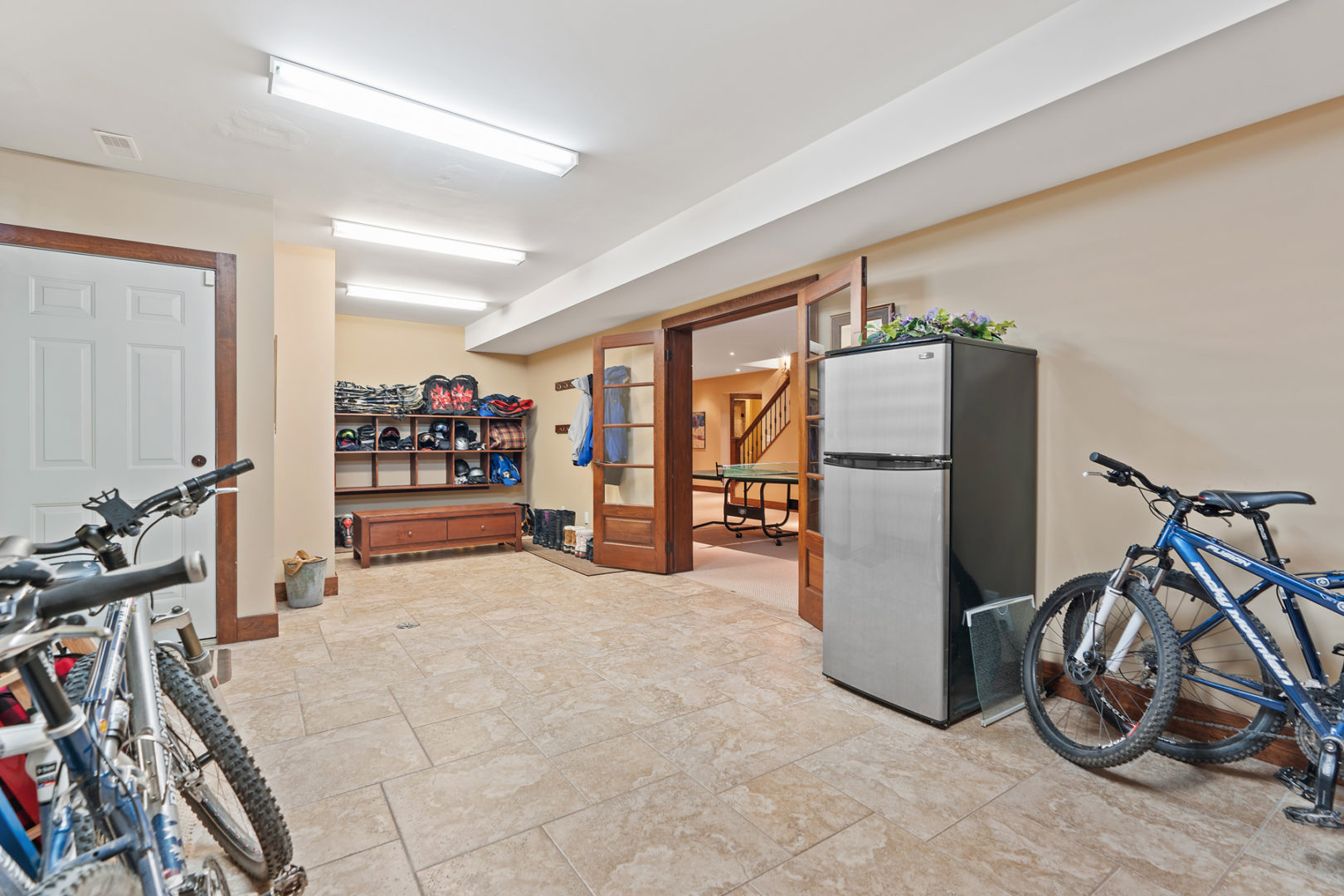 A spacious basement space with a fridge, bike storage, and a mudroom area.