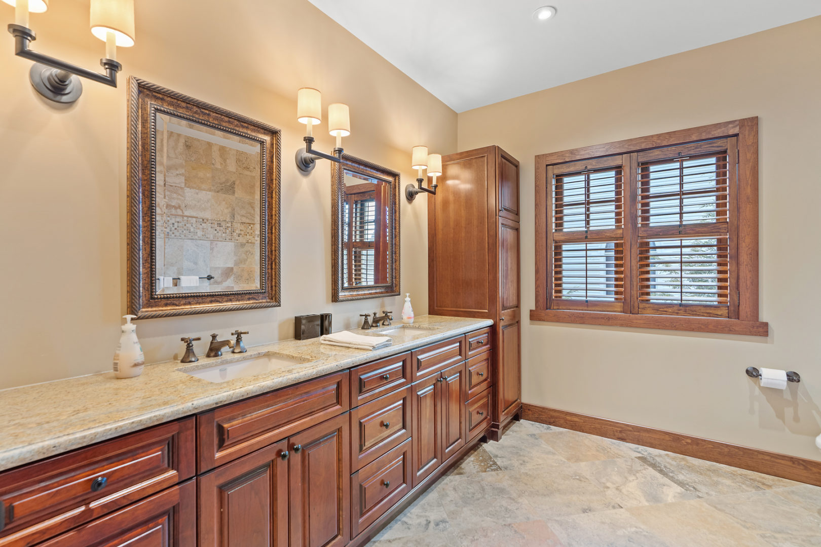 A large bathroom with double sinks and warm wood accents.