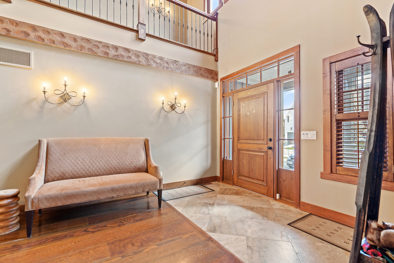 A bright, spacious entryway of a luxury home, with hardwood floors, high ceilings, and a large wooden front door.