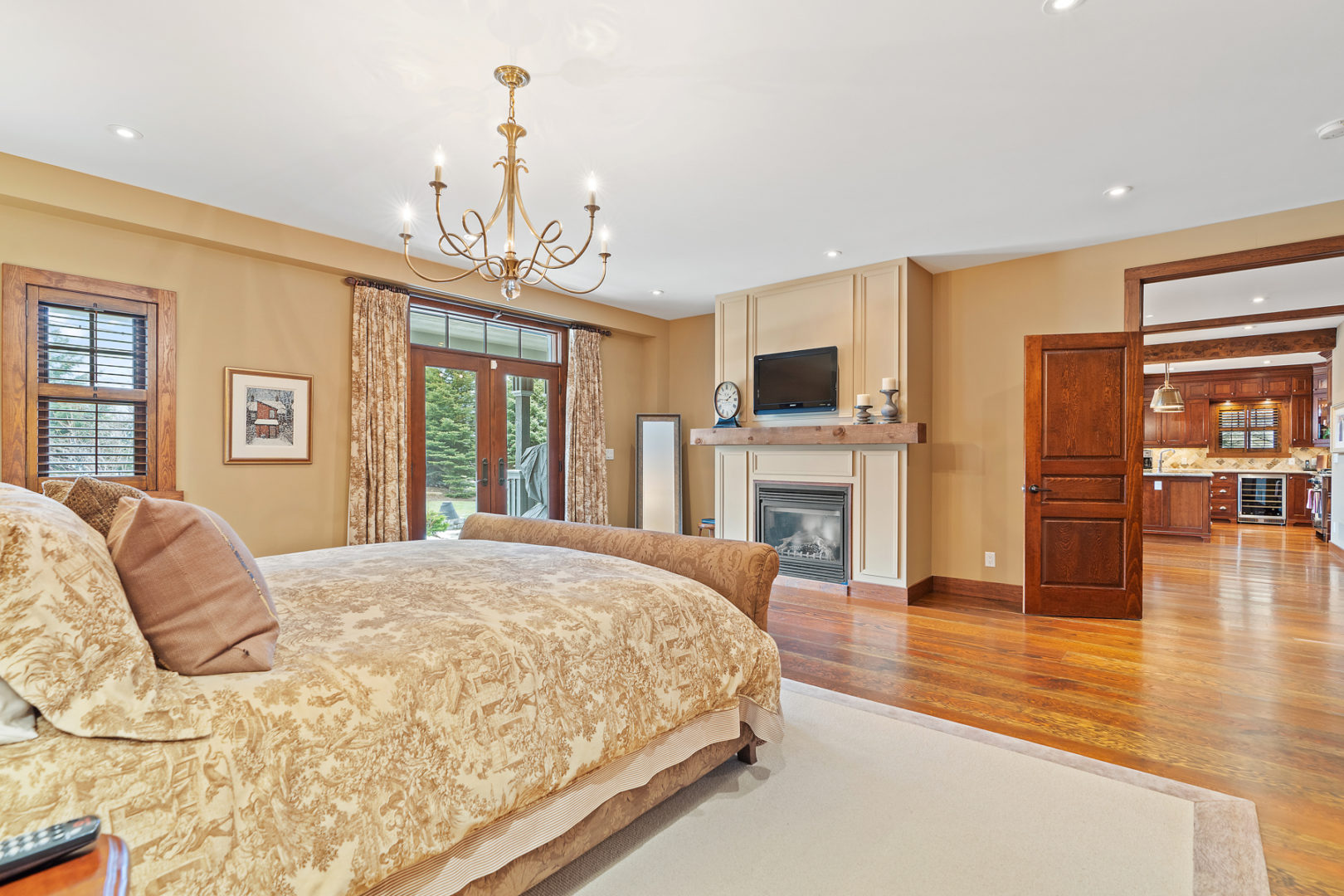 A large primary bedroom with a big bed and double doors leading out to the backyard.