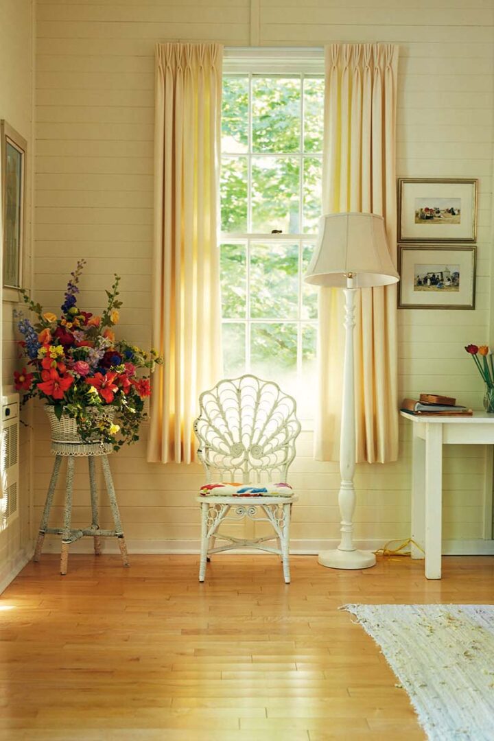 Ornate white whicker peacock chair against a sunny window at the cottage