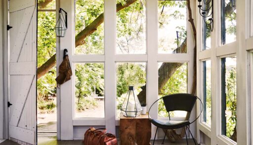 Papasan chair in a bright and sunny room at the cottage with green trees seen through the open windows