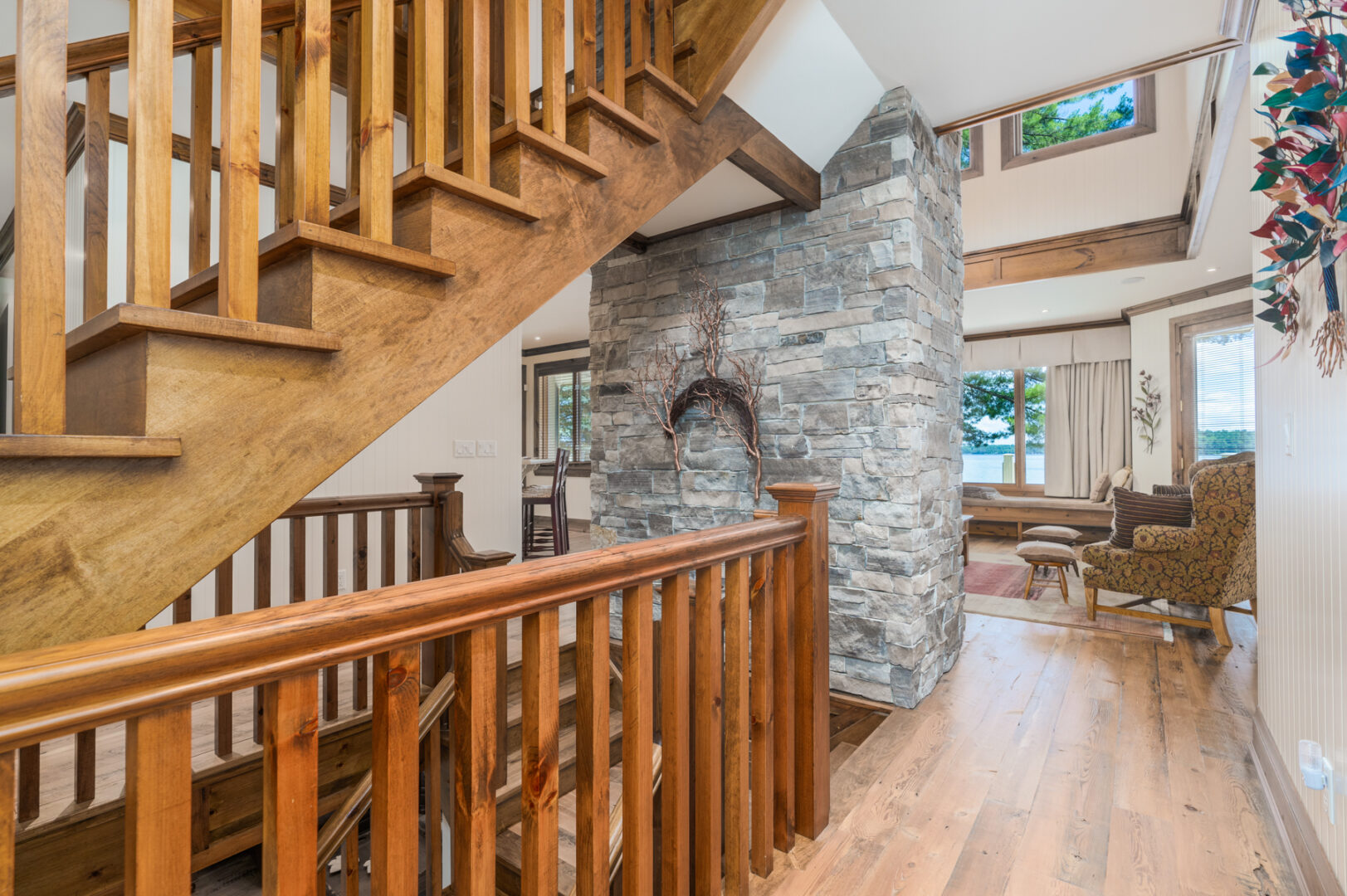 Hallway leading into the main area of a large house, with warm wooden design accents and a large stone fireplace.
