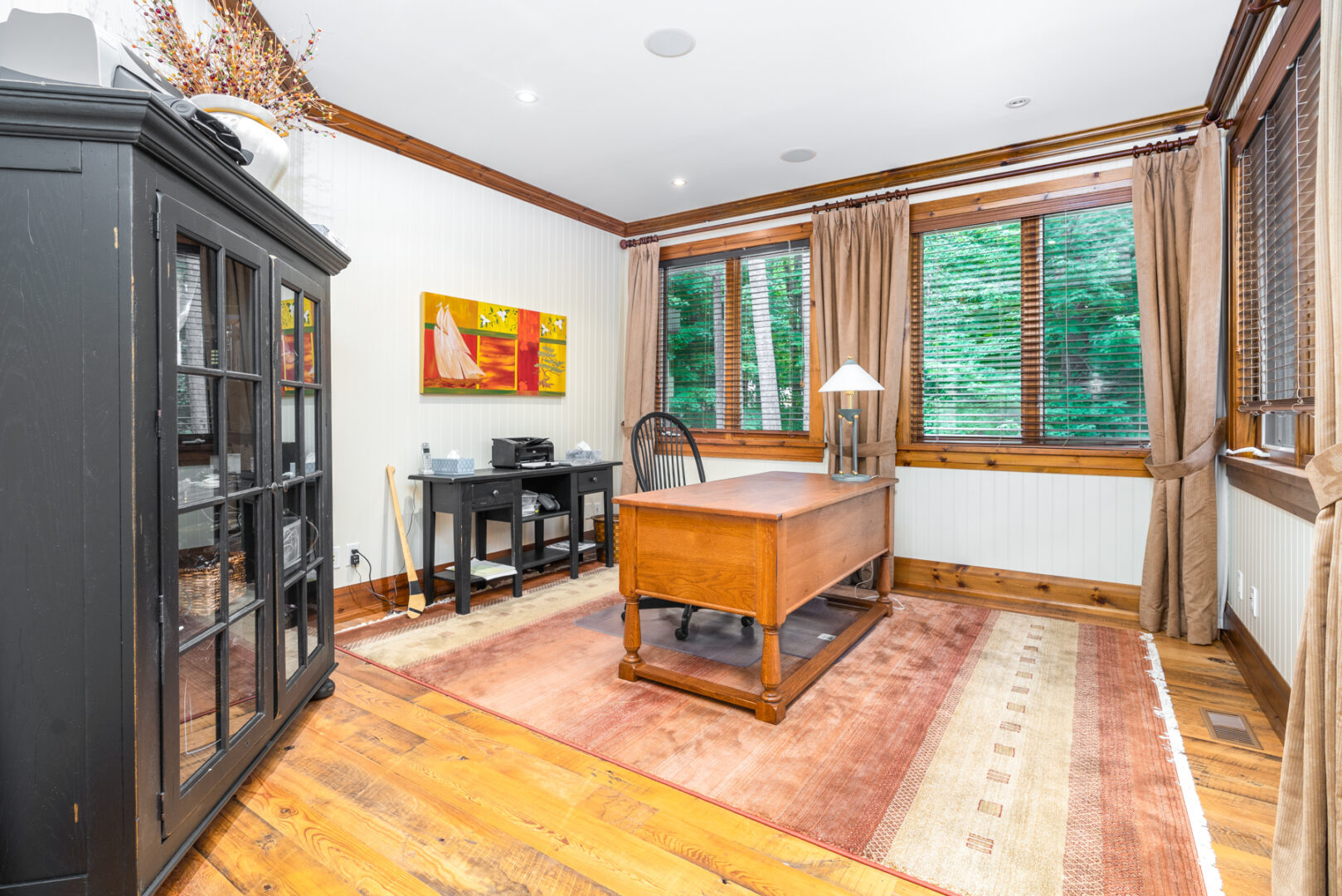 A large room with big windows and a small desk and chair in the middle.
