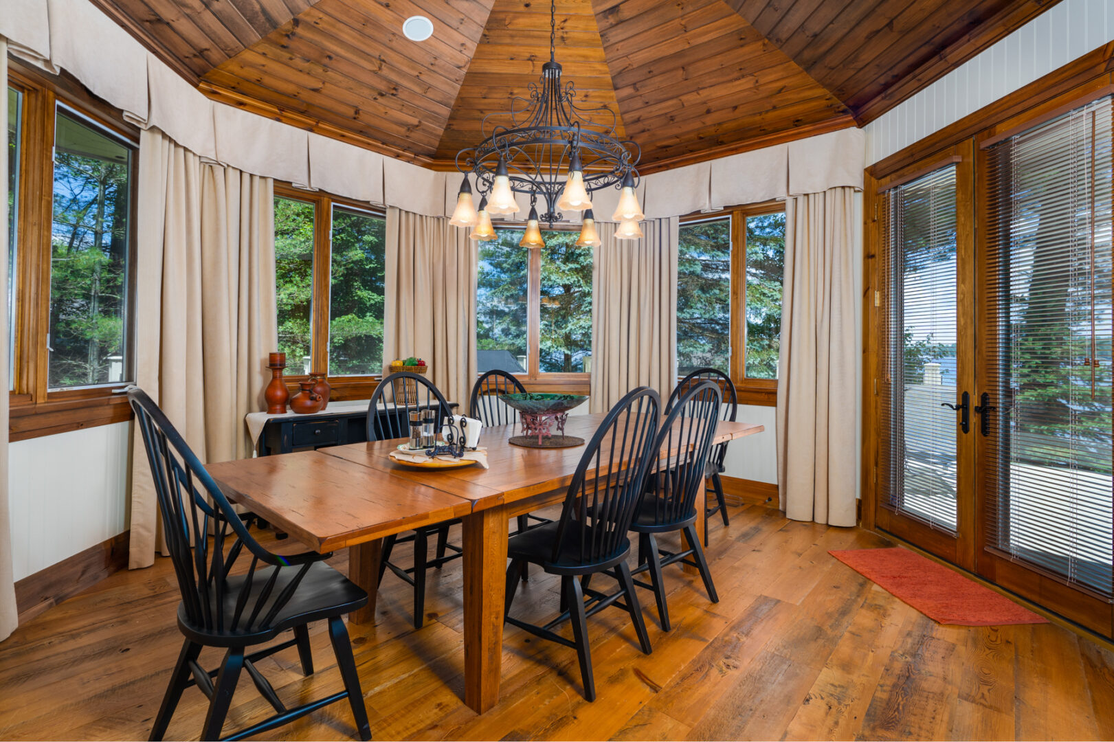A round dining area with windows all around and a table and chairs.