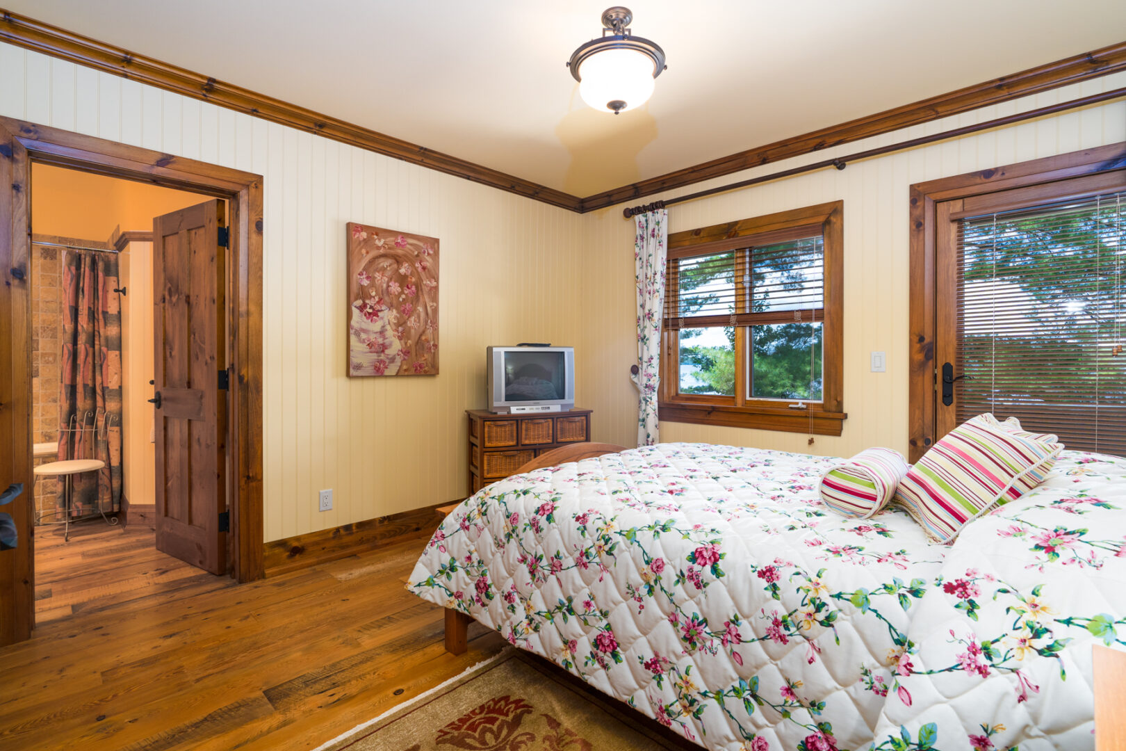 A spacious bedroom with a small bed, large windows, and a doorway leading to a bathroom.