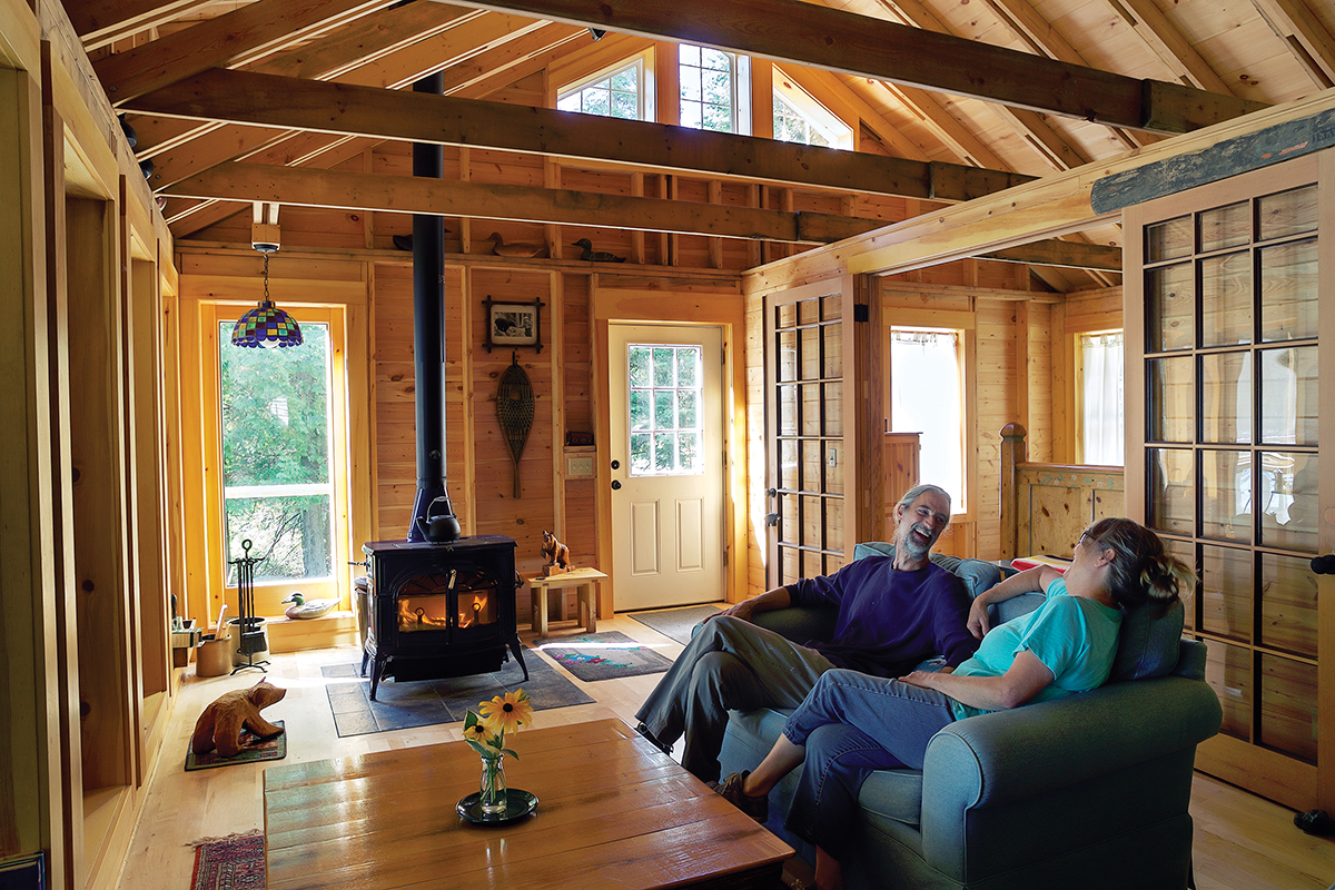 Living room of cottage with two people on the couch in front of a fireplace