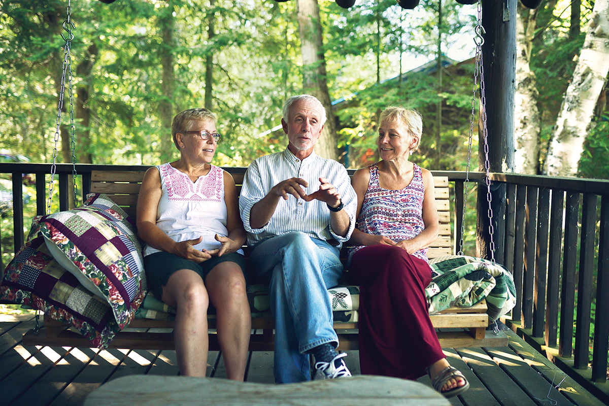 Albert Crowder sits on a porch swing with Brooke Hallowell (right) and her sister at the cottage he built for their mother, Jane Lou Smith.