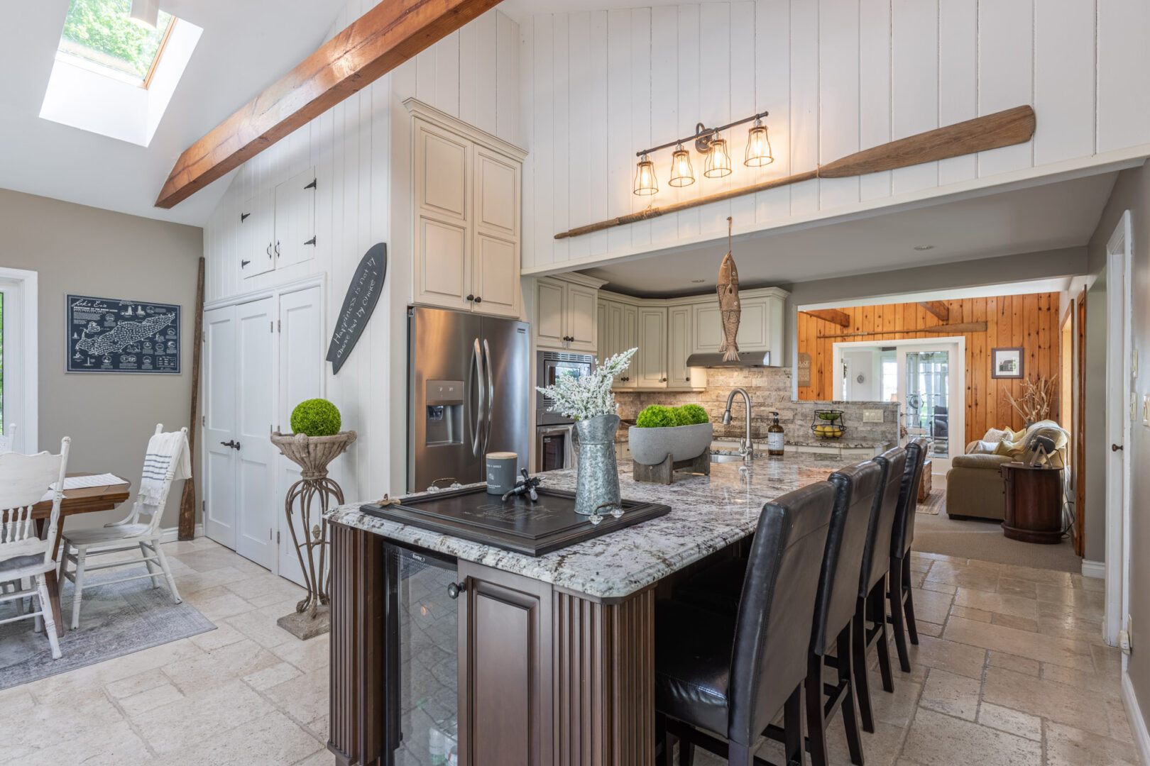 A large, dark granite kitchen island with barstool seating sits in the middle of a big, luxurious cottage kitchen area.