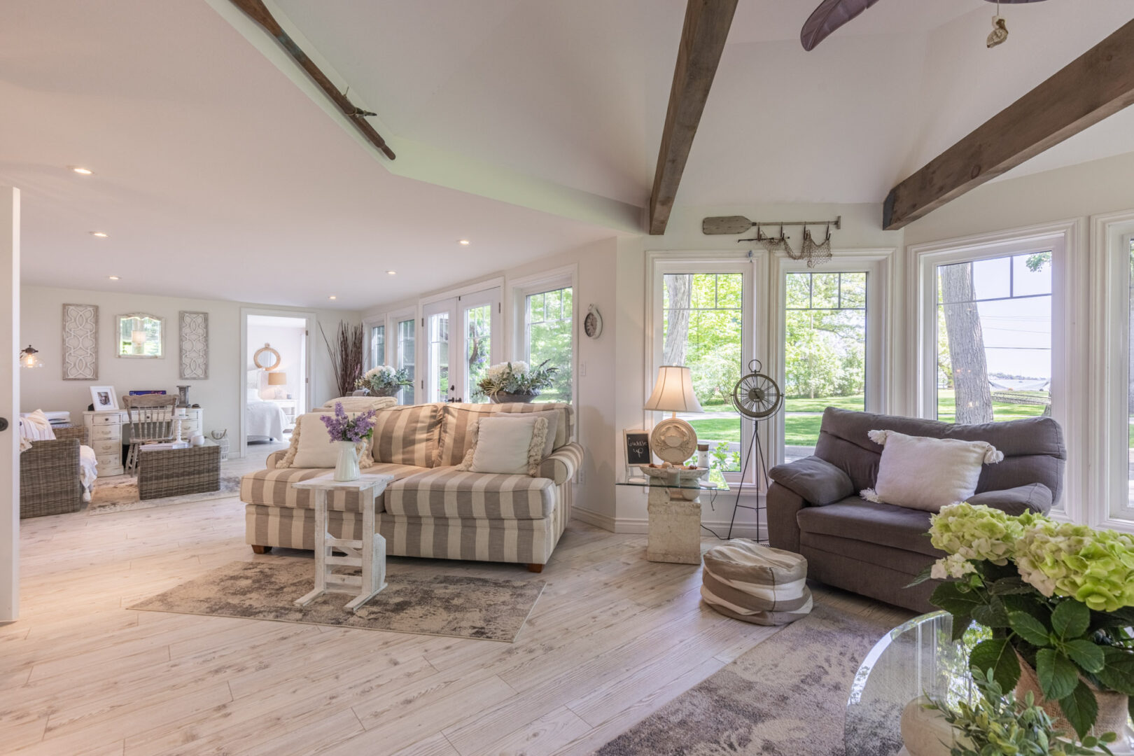 An open-concept space flowing from a bright sunroom with lots of windows to an additional seating area with a couch.
