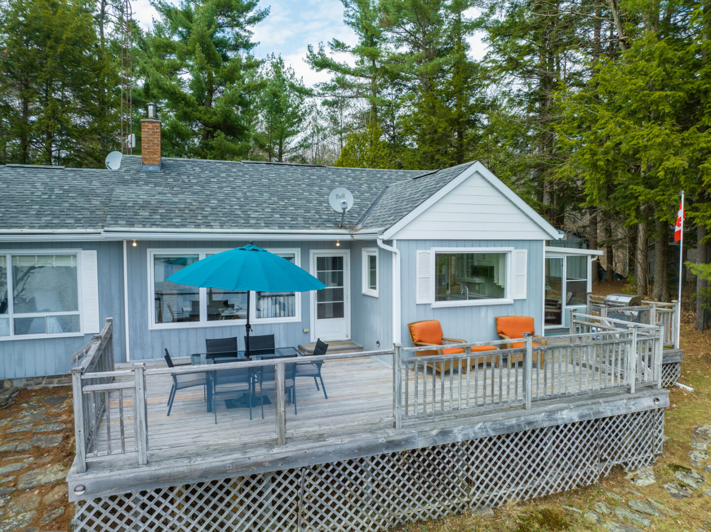 A large deck extends off the waterfront-facing side of a cottage.