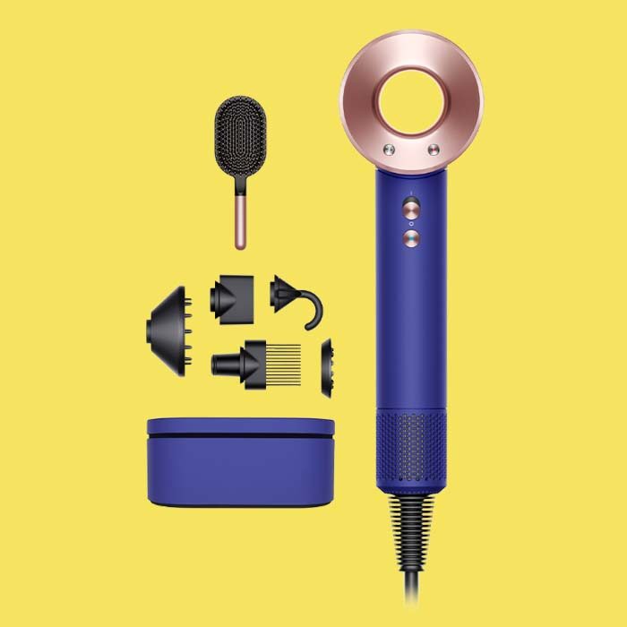 Purple Dyson hair dryer with attachments on a yellow background