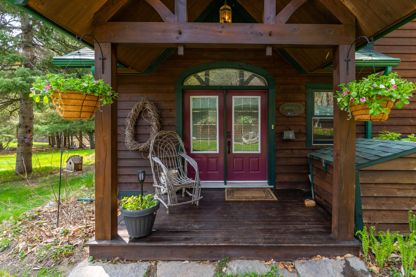 A large, cozy front porch with a rocking chair and big, red double front doors.