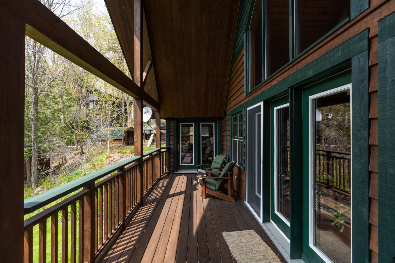 A long, covered deck area with multiple doors leading into a cottage.