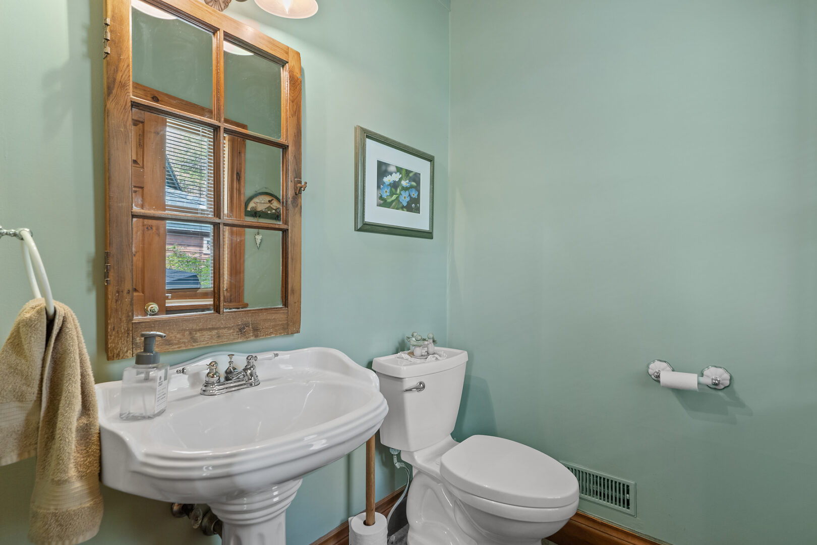 A small bathroom with sage green walls, a toilet, and a sink.