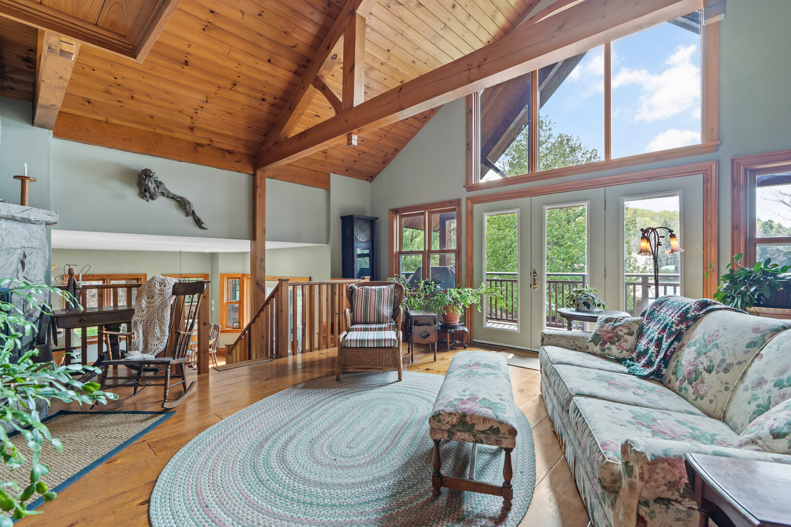 A bright, spacious living area with a couch large windows, and a door leading out to a back deck.