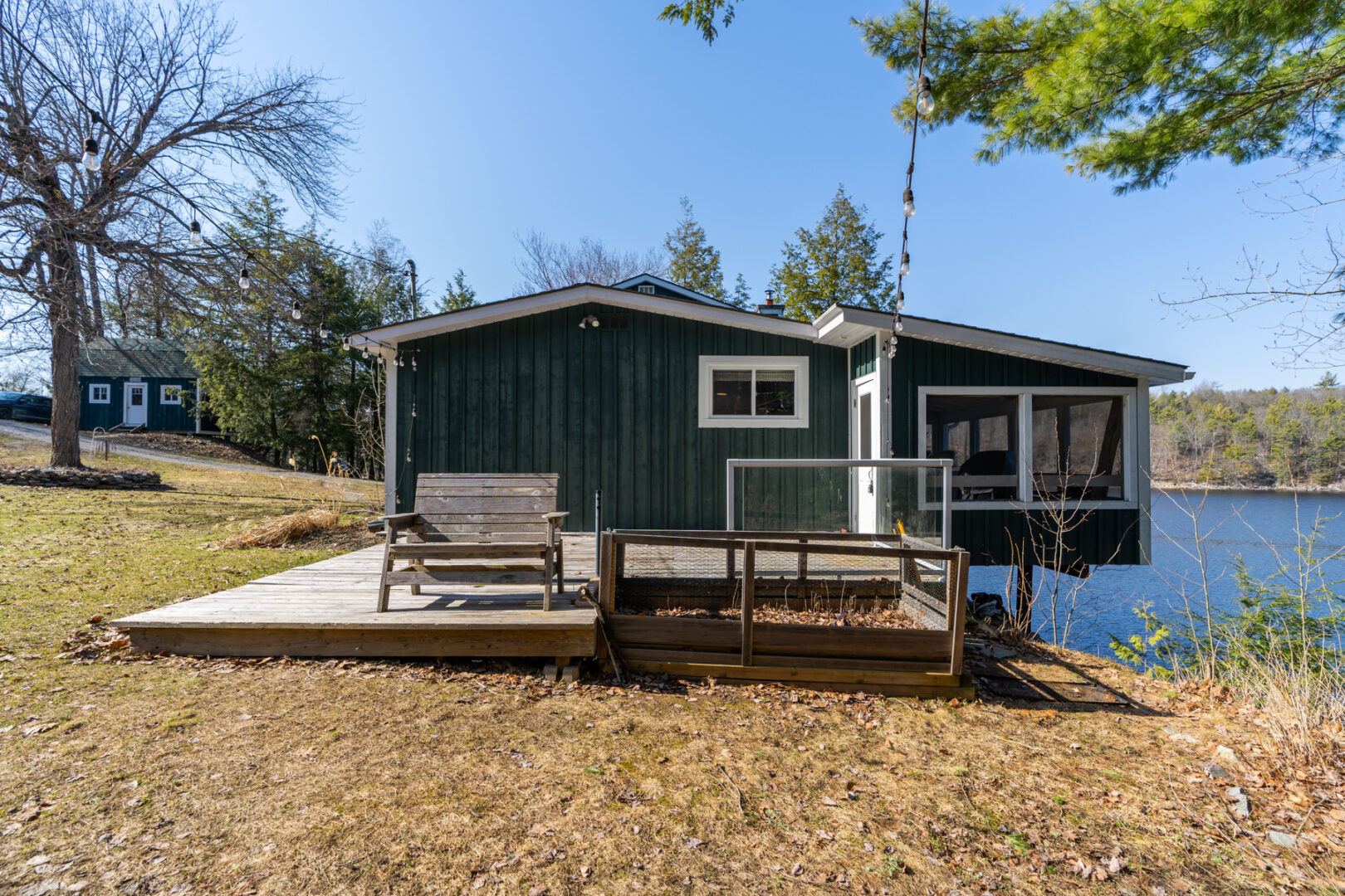 Side view of a green cottage, with a wooden deck extending off the side of the house.