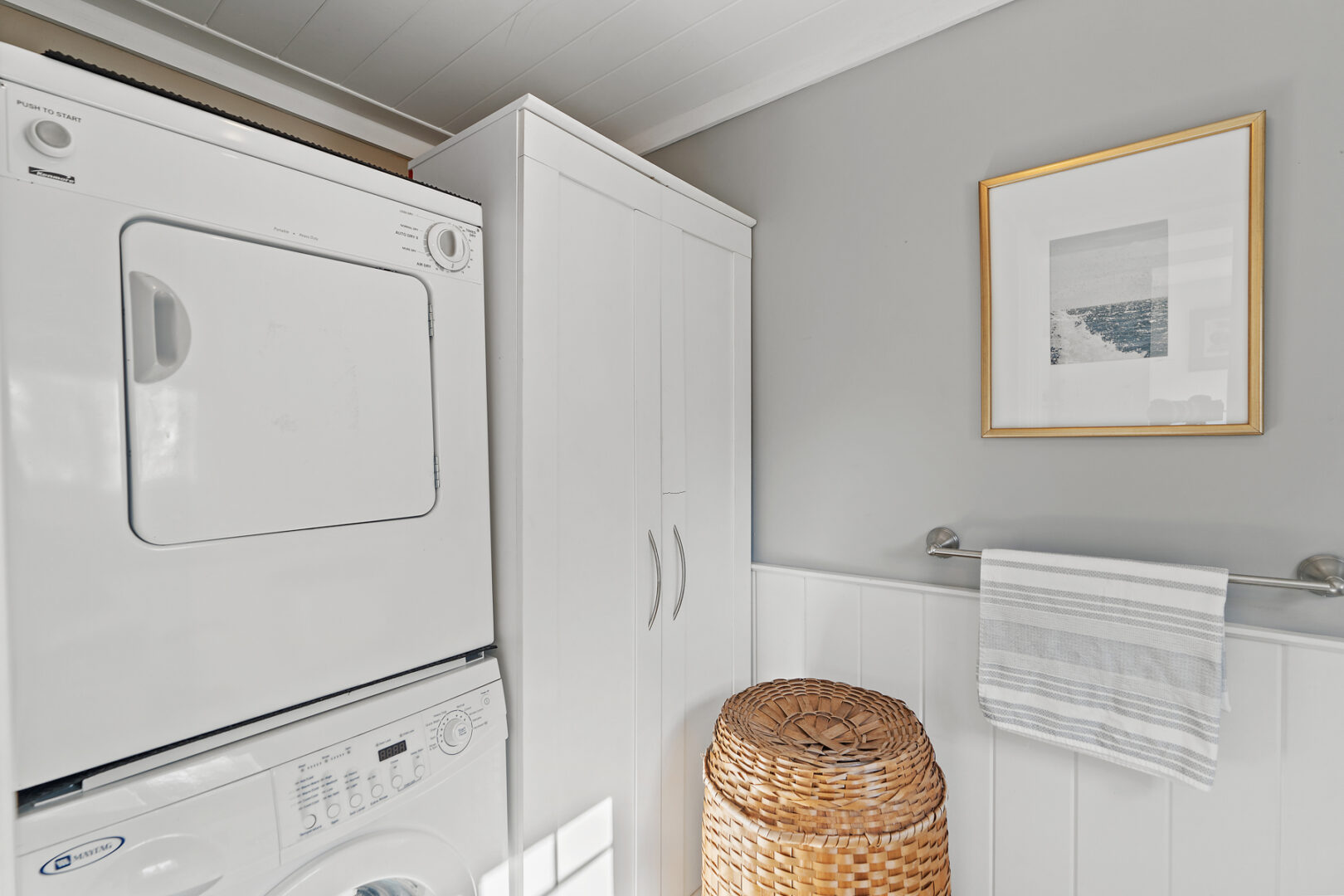A simple laundry space with a washer, a dryer, and a wicker laundry hamper.