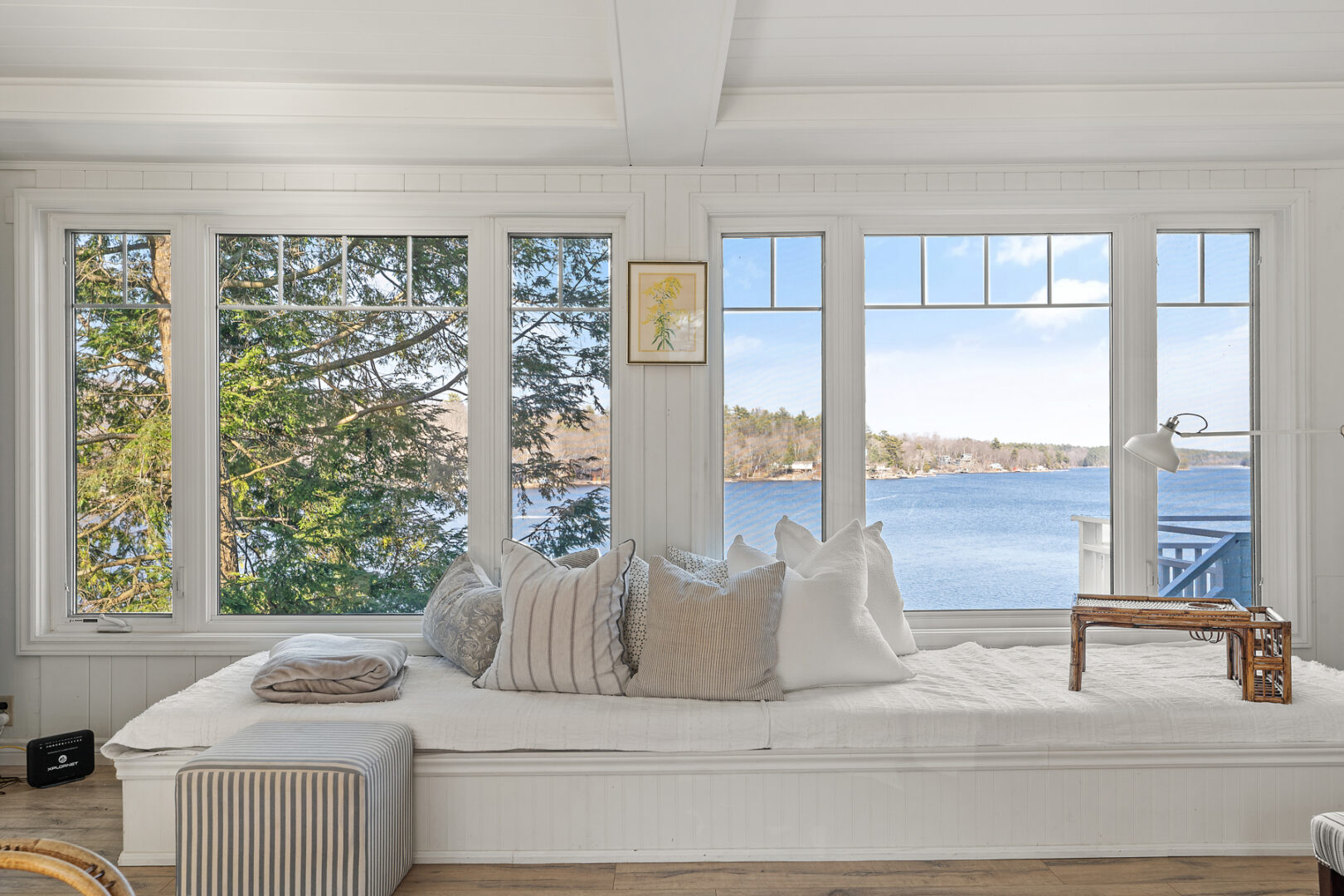 A spacious, white window seat in front of a large window with a view of the lake.