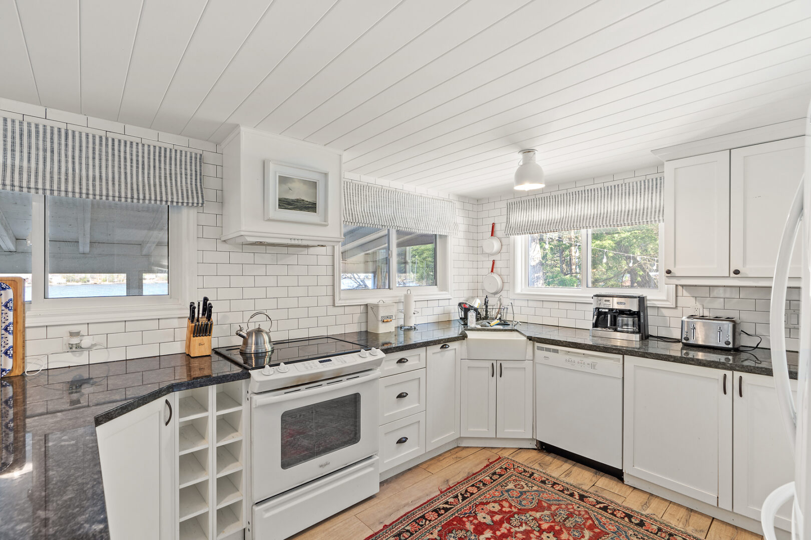 A bright cottage kitchen with white cupboards and appliances.