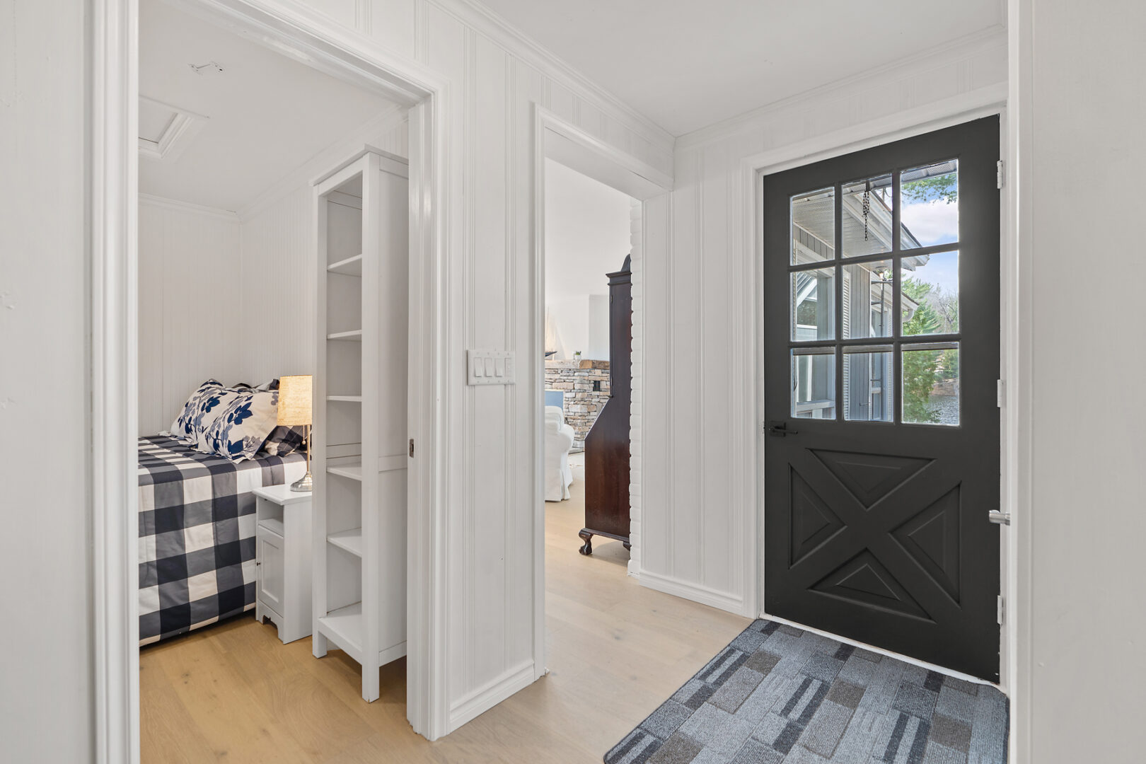 A bright but narrow entrance of a modern-style cottage with white walls and rooms branching off the hallway.