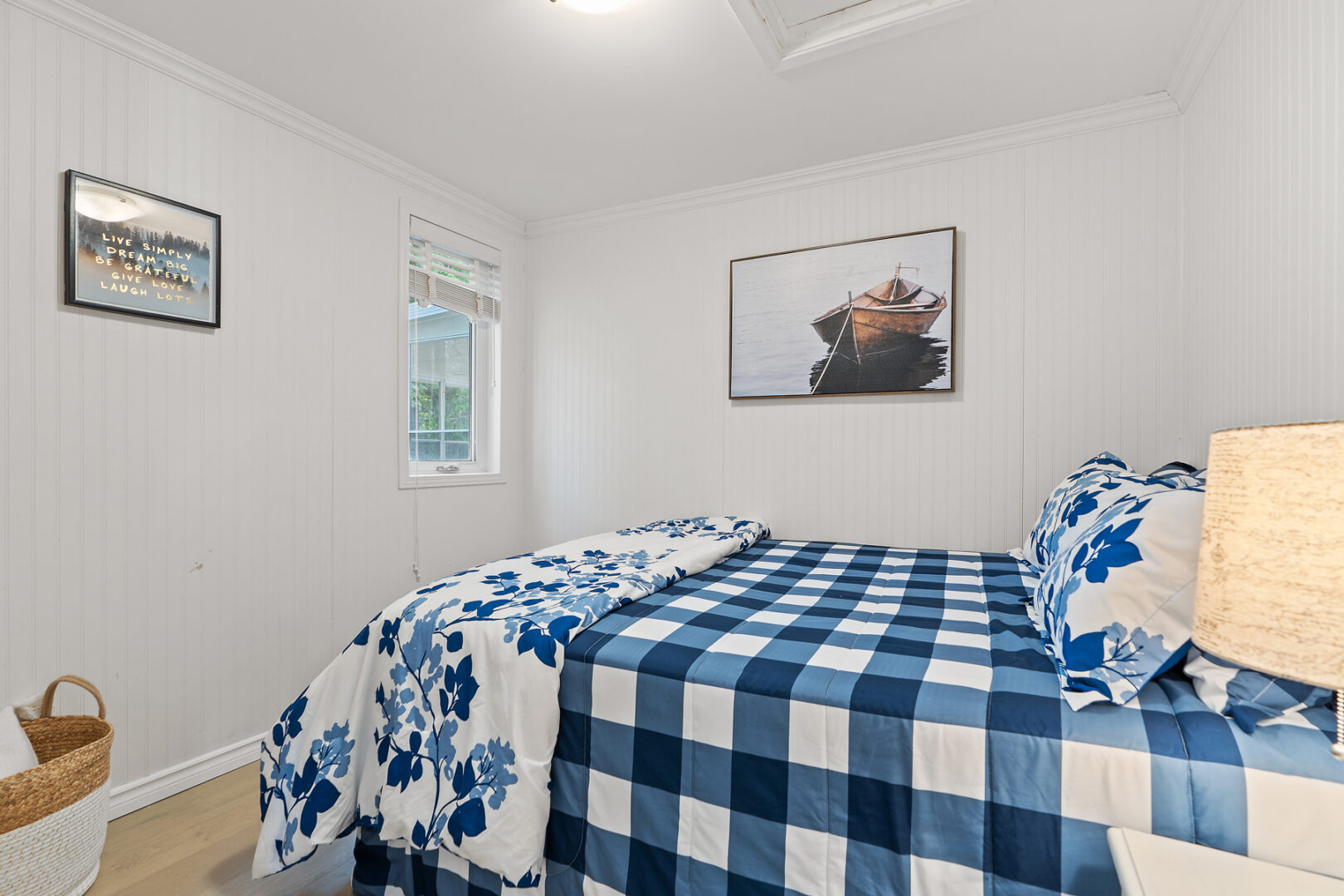 A bright bedroom with white walls and a blue-and-white checkered bedspread.