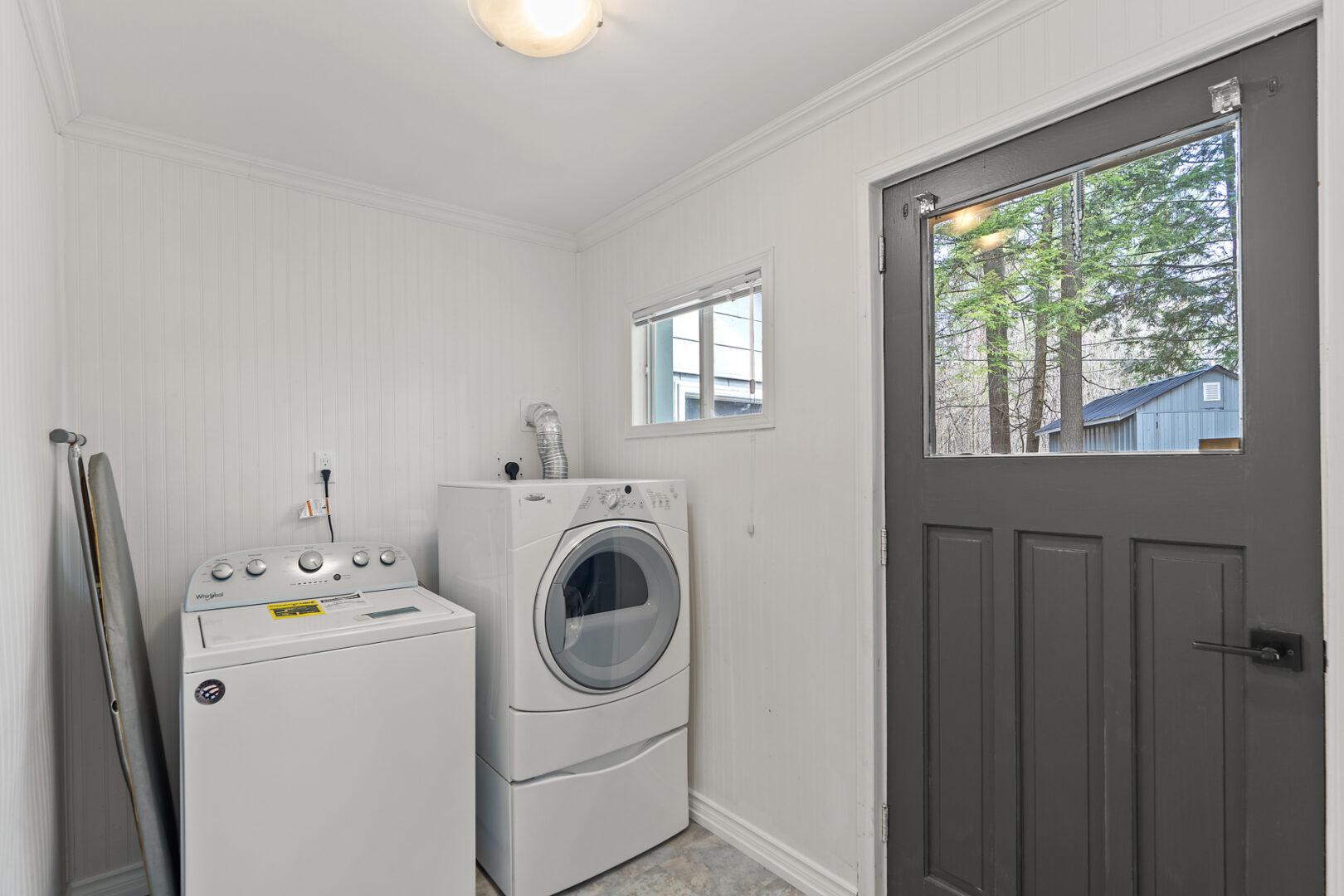 A small space with a washing machine, a dryer, and a door leading to outside.