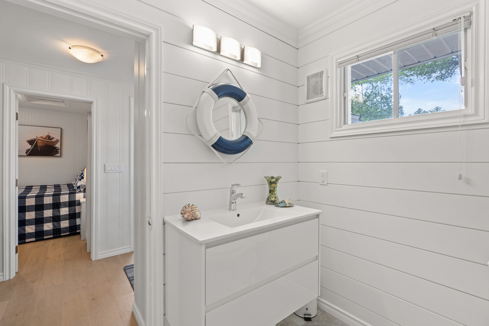A bathroom sink with white walls and cabinetry and a mirror.
