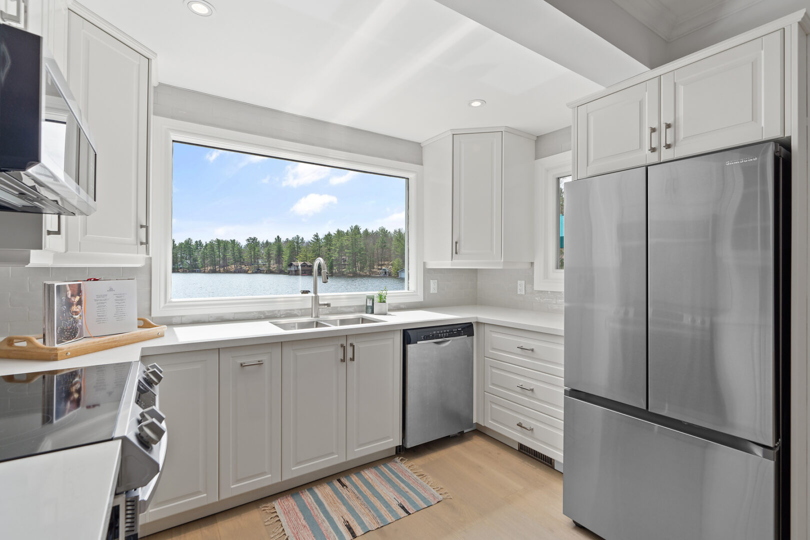 A bright kitchen with white walls and cabinetry and stainless steel appliances.