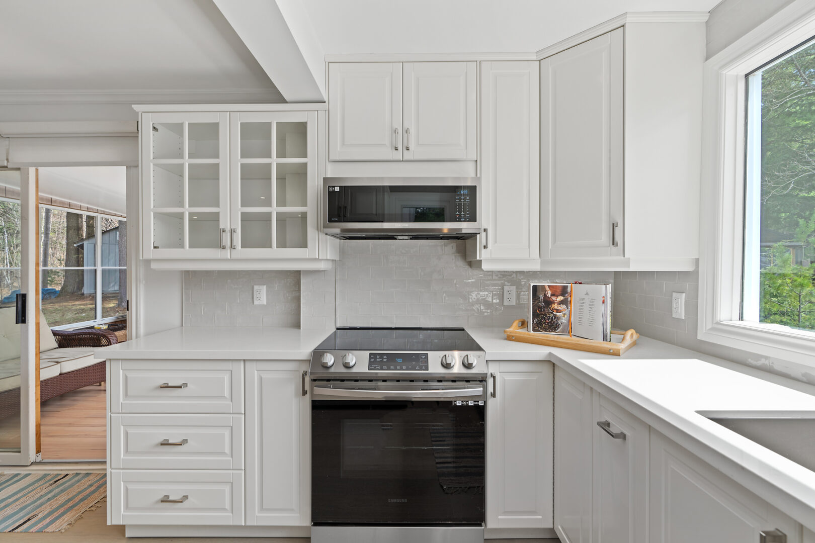 A bright kitchen with white walls and cabinetry and stainless steel appliances.