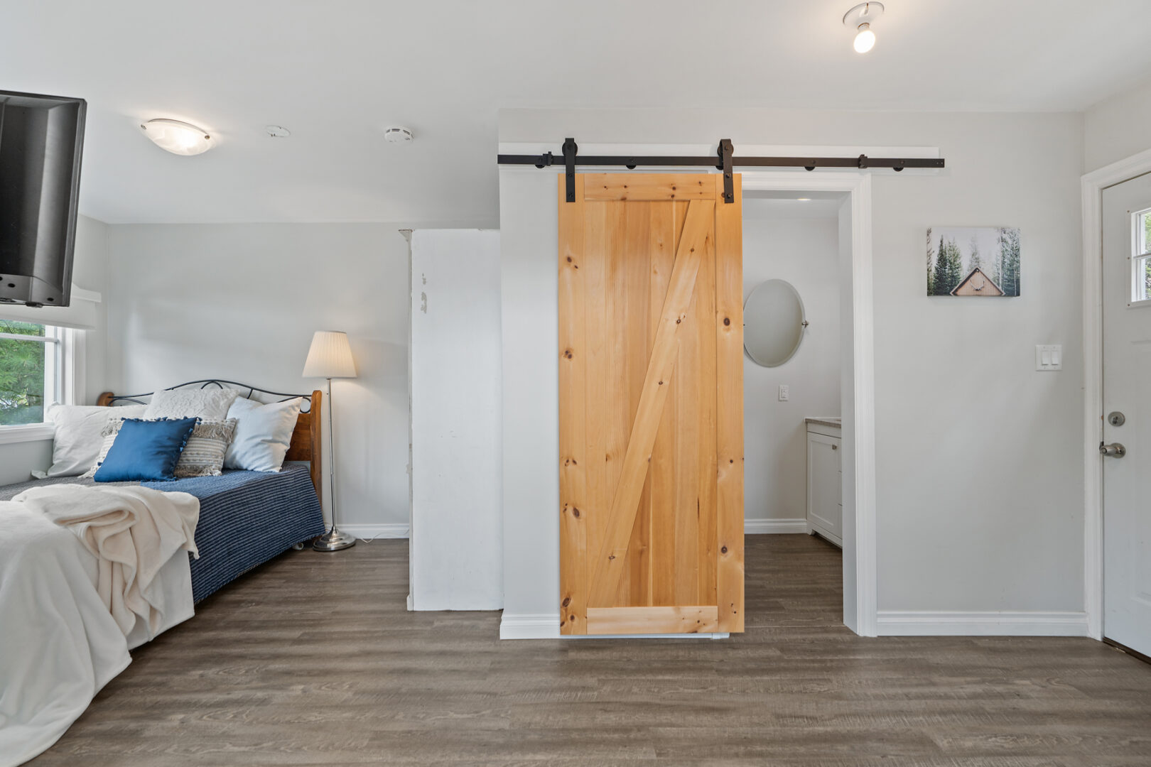 An open-concept studio-style bunkie living space with a bathroom and a bed.