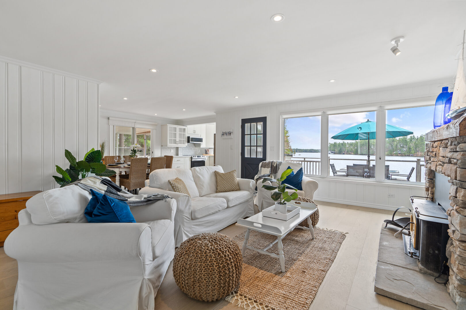 A bright, open cottage living space with couches, large windows, and white walls.
