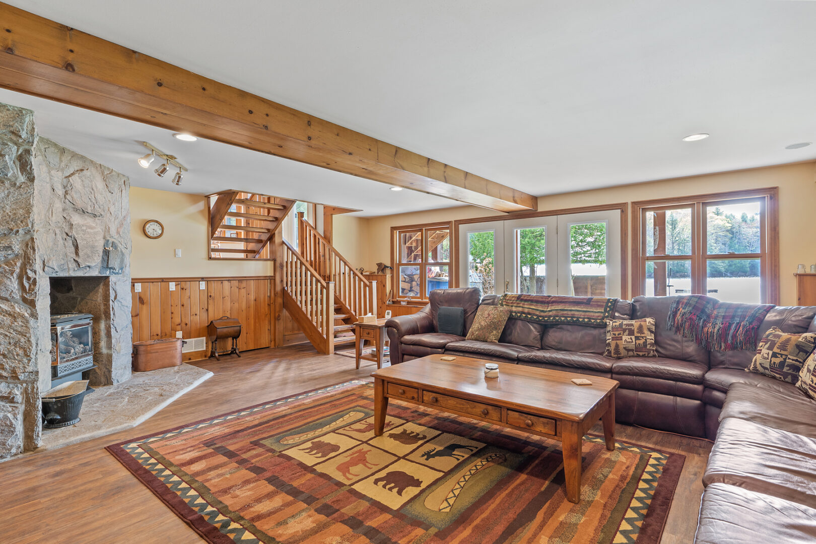 A large lower-level living space with a big L-shaped couch, large windows and a walkout door to the back lawn.